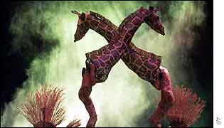 Dancers perform with giraffe puppets at opening ceremony
