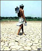 An Indian farmer walking across a dried out lake