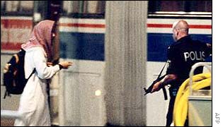A passenger walks toward a bus under police guard