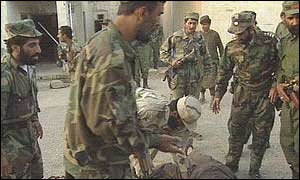 Afghan soldiers stand over the bodies of the assailant, one of Karzai's bodyguards and a third man