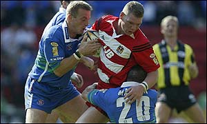 Danny Tickle of Wigan Warriors is tackled by Paul Newlove and Tommy Martyn of St Helens 