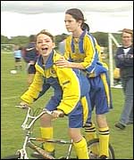 Two girl footballers on a bike