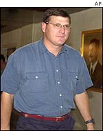 Scott Ritter walking past picture of Saddam Hussein