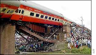 Residents stand by as wreckage lists precariously over a bridge 