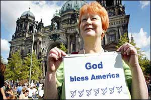 A woman holds a poster in front of the Berlin Dom cathedral 