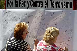 Spaniards write message on a large poster in Madrid; banner reads 'For Peace and Against Terrorism'