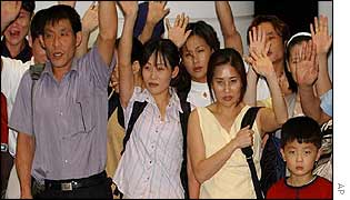 A group of asylum seekers wave as they arrive in Seoul 