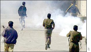 Indian security personnel chase Kashmiri protesters through tear gas