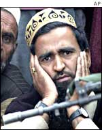 Man listens at rally with armed guard in the foreground