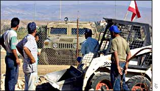Israeli soldiers watch Lebanese workers as they lay water pipes