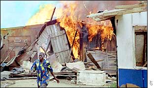 A man walks past a burning shack in Abidjan