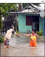 A couple wade through floodwater outside their home, west of Havana