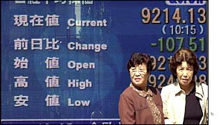 Women standing in front of a stock board in Tokyo