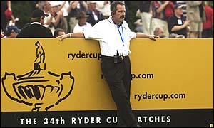European captain Sam Torrance leans on a Ryder Cup advertising hoarding