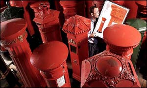 Postman John Taylor, from the Royal Mail's Winchmore Hill delivery office, carries a new issue first class stamp featuring an 1856-design post box through a sea of pillar boxes 