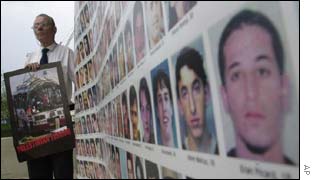 An Israeli protester stands next to a picture of victims of the uprising