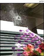 Flowers on a bench under a bullet hole, at the scene of one killing in Aspen Hill, Maryland