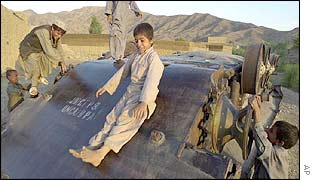 Afghan boys play on an overturned armoured personnel carrier