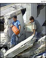 Palestinian children salvage some personal effects found in the rubble of their house which was demolished by Israeli army bulldozers 10 October 2002 in the southern Gaza Strip refugee camp of Rafah