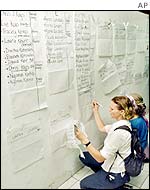 Women in Denpasar check the names of people listed as missing