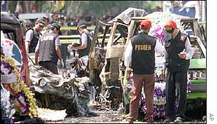 Indonesian policemen walk past flower displays placed at the site of the explosion in Kuta