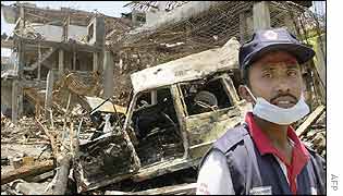 An Indonesian Red Cross worker stands in the rubble