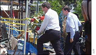 Australian Foreign Minister Alexander Downer (L) offers flowers with Australian Justice Minister Chris Ellison (R) 