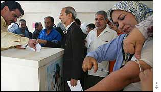 Iraqi woman takes blood from her arm to mark yes on her voting slip 