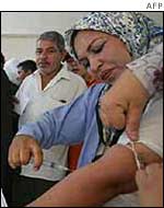 Iraqi woman takes blood from her arm to mark yes on her voting slip 