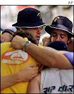 Members of Australian team hug after laying wreath at bomb site
