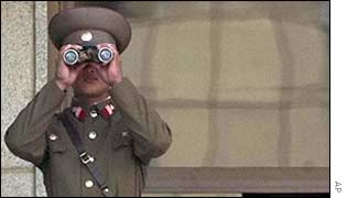 North Korean soldier looks through binoculars across the border with South Korea