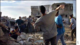 Palestinian youths throw stones at Israeli troops from behind a barricade in the camp 
