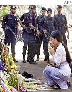 Women pray at the ruins as armed police look on