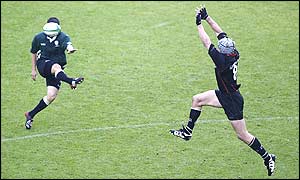 Barry Everitt boots the ball upfield as Simon Taylor tries to charge the kick down