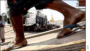 A Burmese labourer walks down a ramp back to a cargo pier to pick up a sack of rice, Rangoon, May 2002