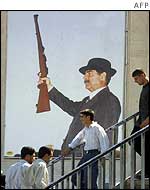 Iraqis in front of a poster of President Saddam
