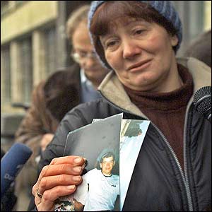 A woman shows photos of her son after failing to locate him at a hospital (AP)