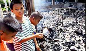 Children look through the remains at a burned down school in Songkhla province
