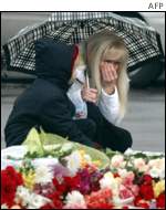 A woman weeps after laying flowers in front of the theatre 