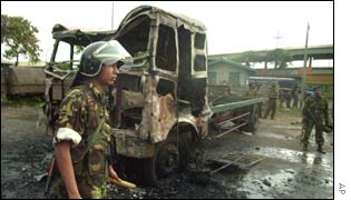 Sri Lankan soldier walks past a damaged lorry, set on fire in Colombo, Sri Lanka