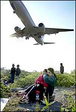 Taiwanese mother holds her son's ears as they watch a plane land at Taipei domestic airport (AP)