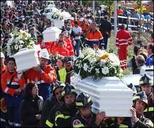 Italian rescuers and armed service workers carry the coffins of victims in procession