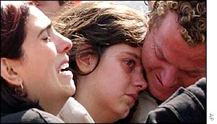 Couple hug each other as another woman cries