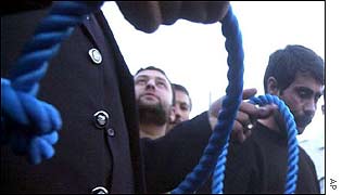 Iranian officials with a noose for a convicted killer (right)