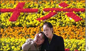 People walk past a flower garden featuring Chinese characters which mean 