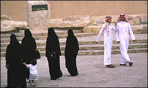 Women in black pass men on a Riyadh street