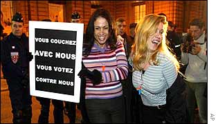 Prostitutes hold banners outside parliament in Paris as riot police look on