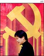 A woman walks past a banner the hammer and sickle, the emblem of the Communist Party