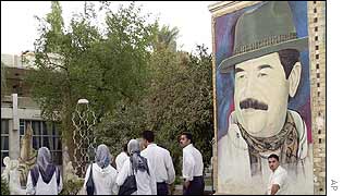 Iraqis walk past a billboard of Saddam Hussein