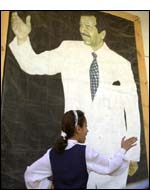 An Iraqi schoolgirl plays in front of a poster of President Saddam Hussein